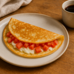 Crepe salgado dobrado com queijo minas derretido e tomate em prato claro, ao lado de café coado