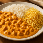 Prato de estrogonofe de frango cremoso com arroz branco e batata palha em mesa de almoço caseiro