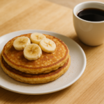 Panquecas de banana com aveia empilhadas em prato branco sobre mesa de café da manhã brasileira